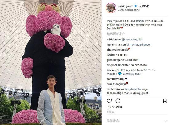 王子在大秀現場巨大的 KAWS 形象玩偶前留影